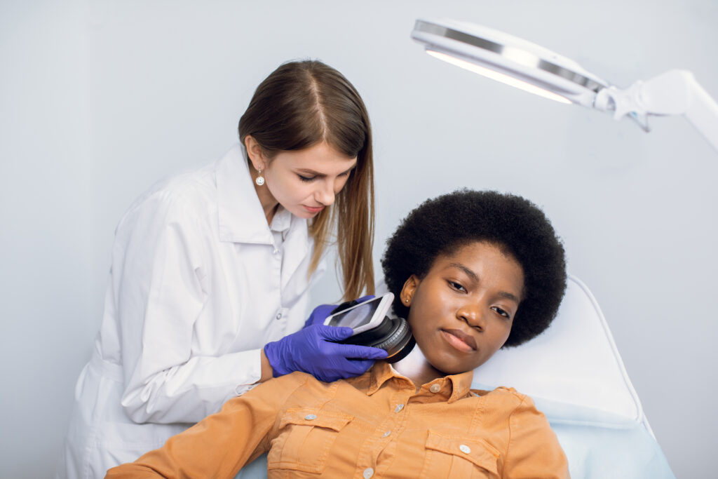 Young African American woman client lying on the couch in modern dermatology clinic, having face