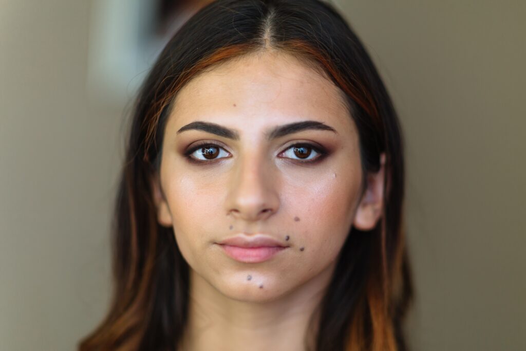 Close-up portrait of young model with moles with makeup in beauty salon